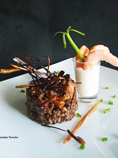 Una foto de Arroz negro, crujiente de puerro y langostinos alioli
