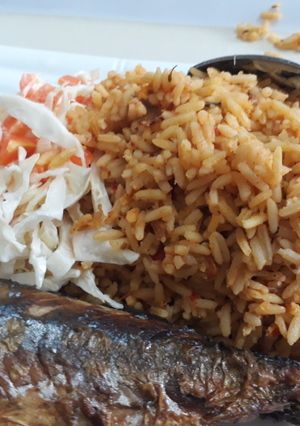 A picture of Jollof rice coslaw with fried fish.