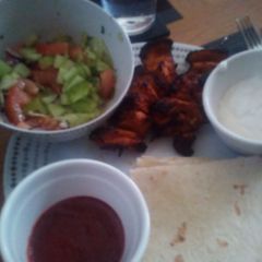 A picture of Grilled Chicken Kebabs, salad and wraps with dips.