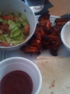 A picture of Grilled Chicken Kebabs, salad and wraps with dips.