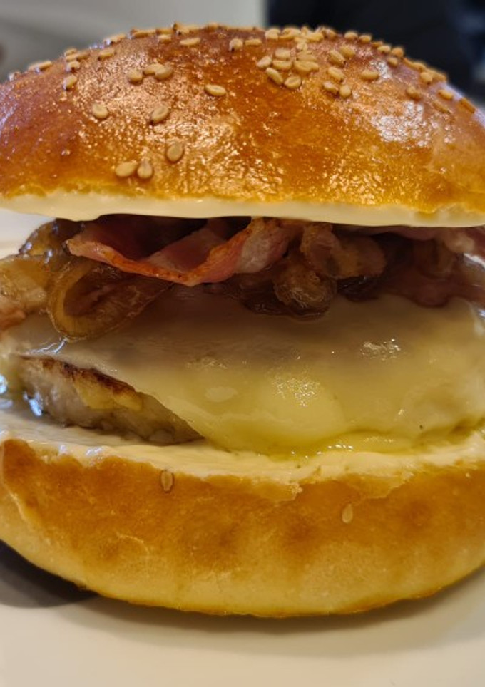 Una foto de Hamburguesa de pollo al curry, cebolla caramelizada, queso-bacon