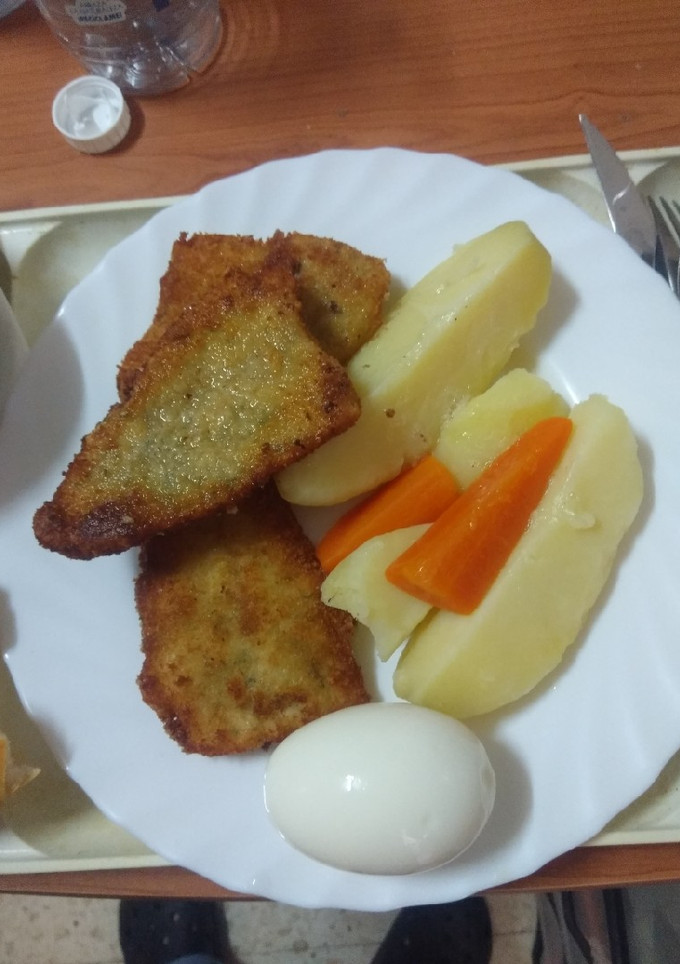 Una foto de Merluza empanada con papas cocidas, zanahoria y huevo duro