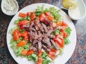 Una foto de bistec con ensalada