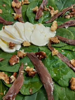 Una foto de Ensalada de espinacas, queso cabra, anchoas y nueces