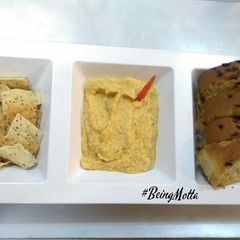A picture of Hummus with Baked Nakmeen and Garlic Bread.