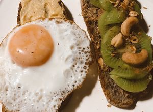 Una foto de Tostadas de pan de arándanos con kiwi 🥝,anacardos y hummus con huevo 🤍