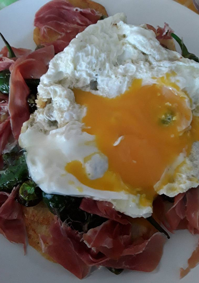 Una foto de Huevos rotos con jamón y pimientos de Padrón