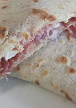A picture of Speck, brie and red onion piadina.