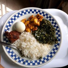 A picture of White rice with vegetable, peppered chicken, boiled egg and diced plantain.