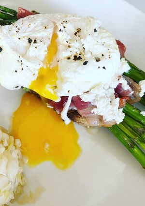 Una foto de Pan con huevo escalfado, espárragos y tocino