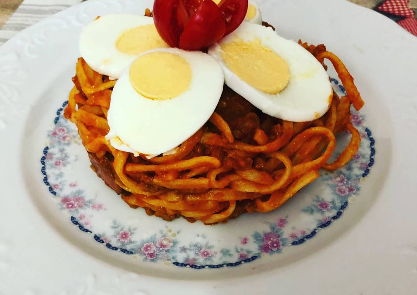 Tallarines a la boloñesa con huevo duro y flor de tomate cherry