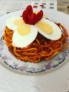 Una foto de Tallarines a la boloñesa con huevo duro y flor de tomate cherry
