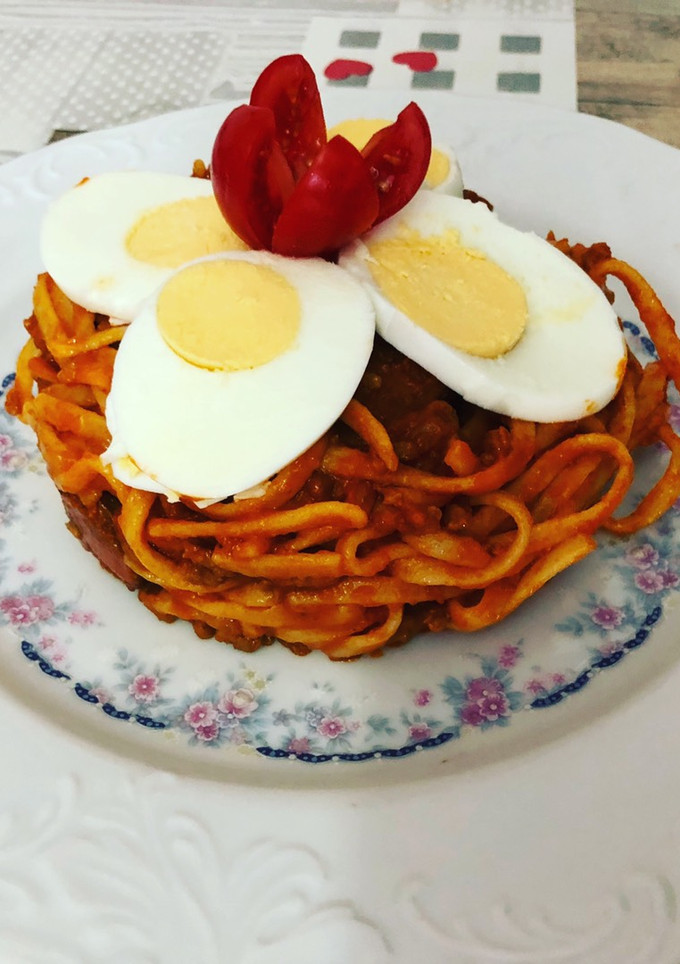 Una foto de Tallarines a la boloñesa con huevo duro y flor de tomate cherry