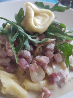 Una foto de Tortelini con salsa de queso suave, Jamón y rúcula