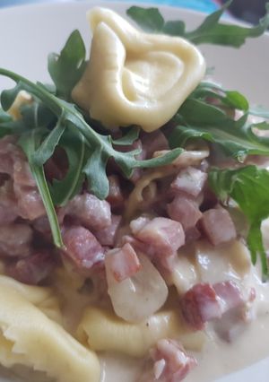 Una foto de Tortelini con salsa de queso suave, Jamón y rúcula