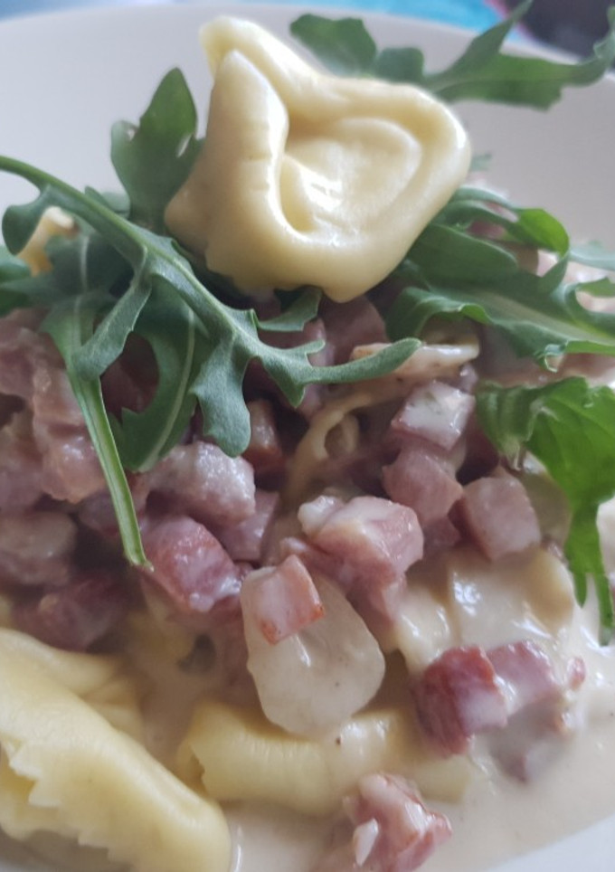 Una foto de Tortelini con salsa de queso suave, Jamón y rúcula