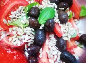 Una foto de Ensalada de tomate, albahaca, aceitunas y semillas de maravilla