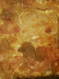 Una foto de Pizza de atún, jamón york, queso rulo de cabra, bacon y cebolla