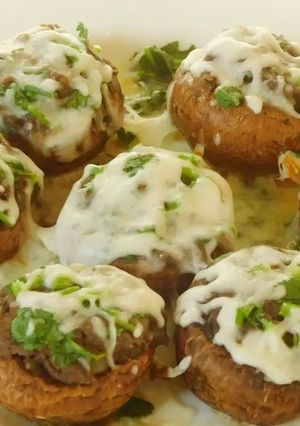A picture of Hummus stuffed cheesy mushrooms.