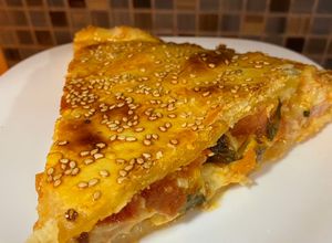 Una foto de Torta de jamón, provolone, tomate y albahaca