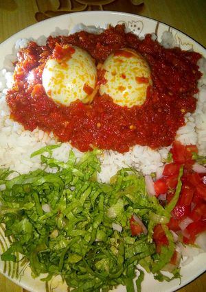 A picture of Rice and stew with eggs and salad.
