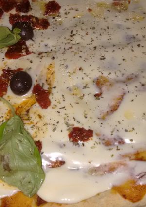 Una foto de Pizza mitad con tomates secos y albahaca