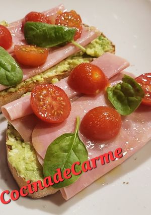 Una foto de Tostas con crema de aguacate y queso, jamón york y cherries