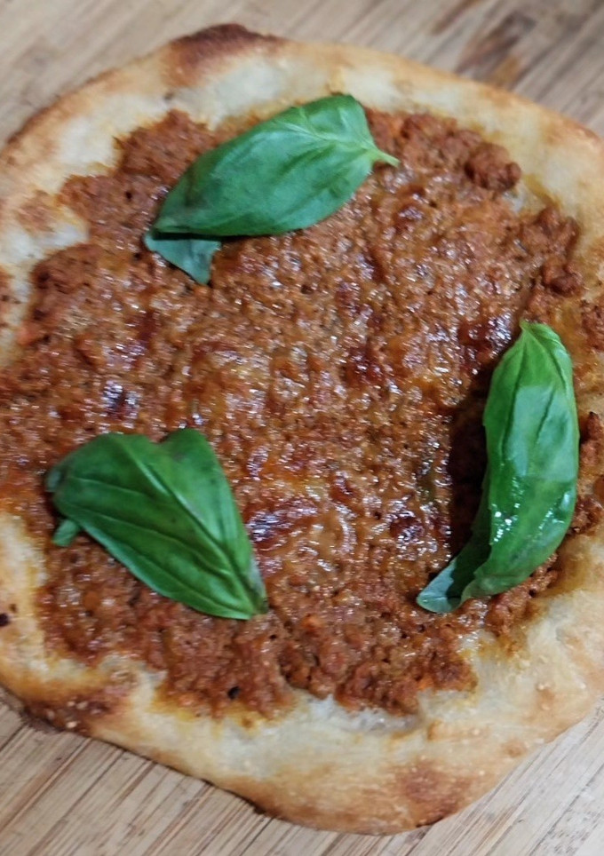 Una foto de Pizza de boloñesa con albahaca