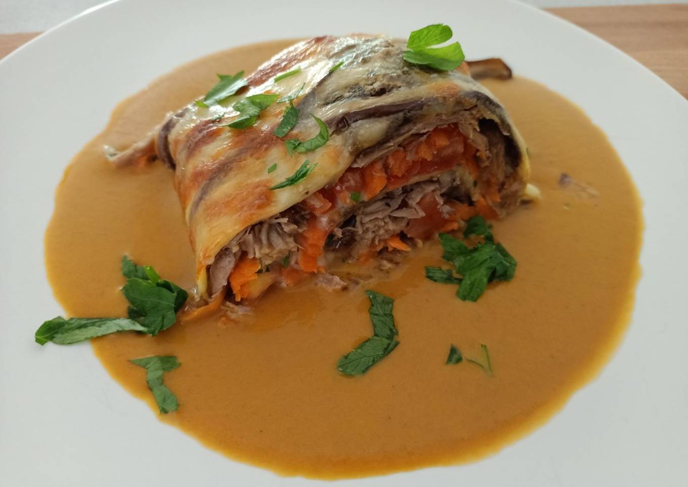 Rulo de berenjena relleno de carne y verduras en su salsa