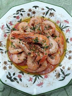 Una foto de Gambas al ajillo y perejil con fondo de tomates