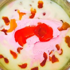 A picture of Dry fruits custard with strawberry ice cream dollop.