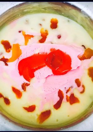 A picture of Dry fruits custard with strawberry ice cream dollop.