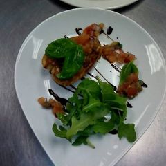 A picture of Tomato and garlic bruchetta with rocket and balsamic glaze.