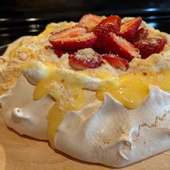 A picture of Pavlova with lemon curd and strawberries.