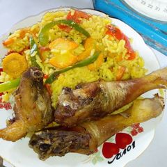A picture of Garnished rice with fried chicken.