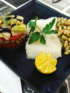 Una foto de Bacalao plancha con timbal de legumbre con pimientos asados, tomate natural y lechuga