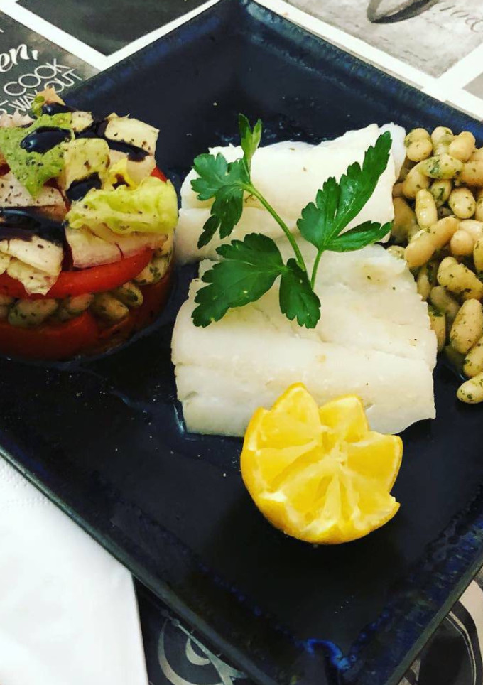Una foto de Bacalao plancha con timbal de legumbre con pimientos asados, tomate natural y lechuga