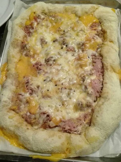 Una foto de Pizza de pollo y jamón york con los bordes relleno de queso cheddar