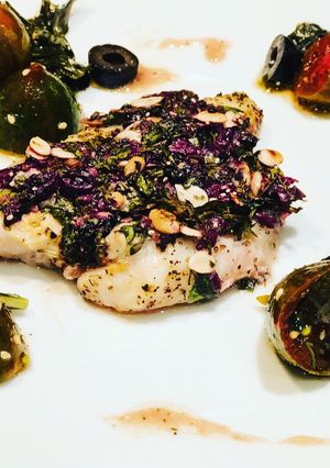Una foto de Pescado en Costra de Semillas y Aceitunas Negras, acompañado de Uvalinas y Aceitunas en Ensalada