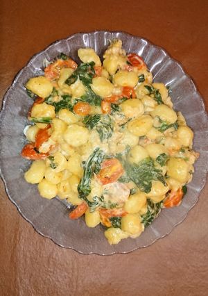 Una foto de Ñoquis con tomate y espinacas