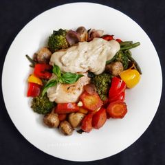 A picture of Olive oil & Butter Poached Chicken with veggies in white sauce.