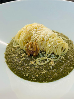 Una foto de Spaghetti verde con crema de espinaca, queso parmesano y polvo de nuez