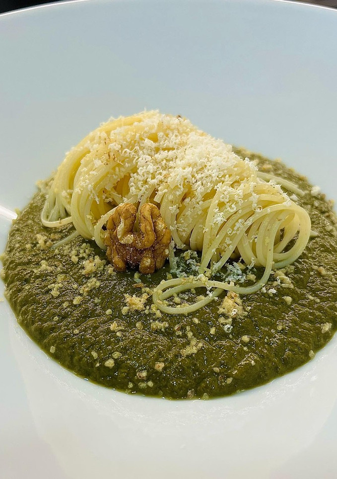 Una foto de Spaghetti verde con crema de espinaca, queso parmesano y polvo de nuez