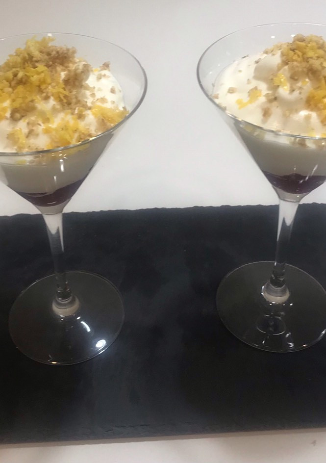 Una foto de Mousse de limón con mermelada de arándanos y crujiente de nueces y ralladura de limón