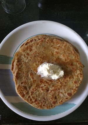 A picture of Aloo pyaz Paratha with white butter.