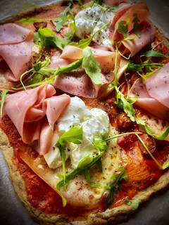 Una foto de Pizza proteica con tomate, burrata y rúcula
