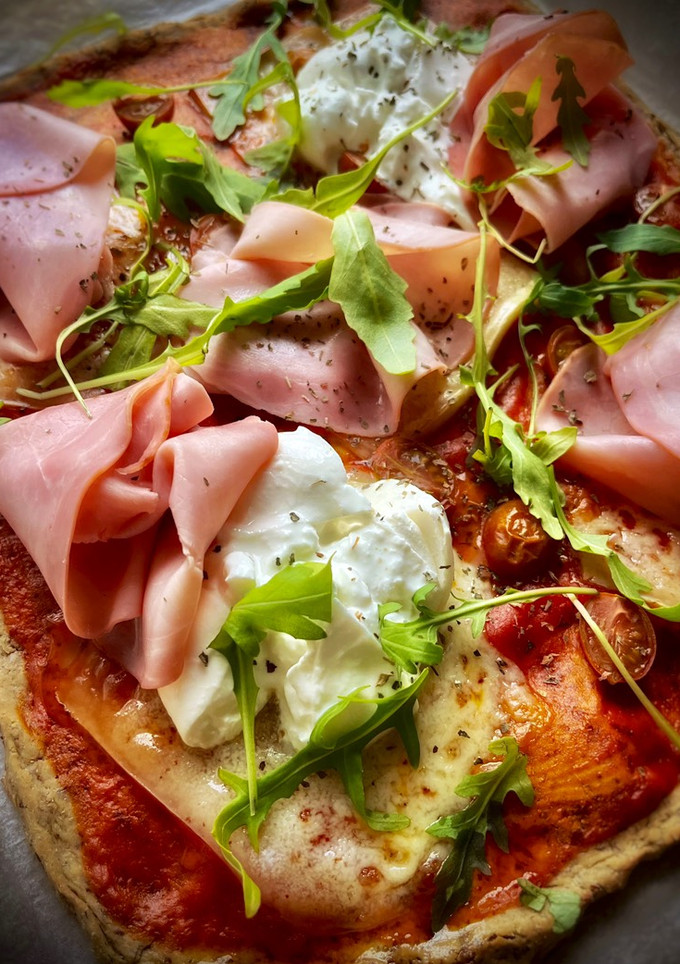 Una foto de Pizza proteica con tomate, burrata y rúcula