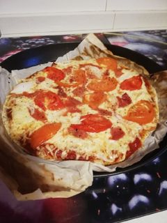 Una foto de Pizza de tomate, jamón y cebolla