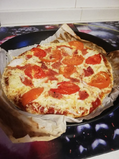 Una foto de Pizza de tomate, jamón y cebolla