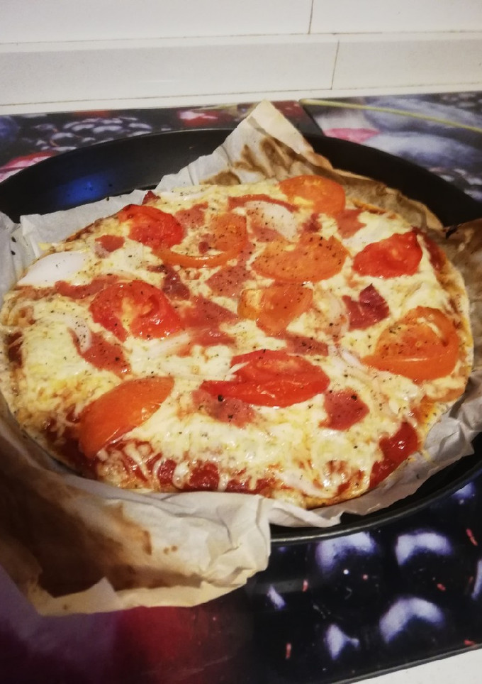 Una foto de Pizza de tomate, jamón y cebolla